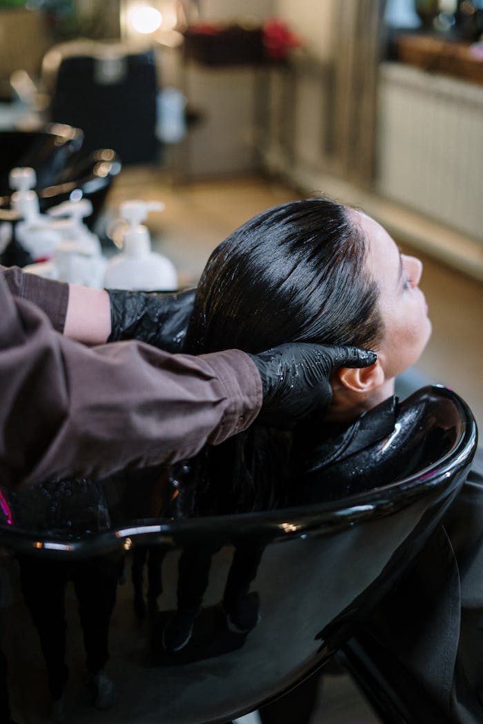 A professional hairstylist washing a woman's hair in a modern salon setting, ensuring quality haircare.
